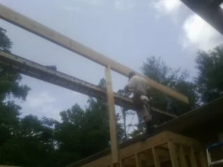 Carpenter setting a ridge beam over a new addition frame — Ice Dam Removal by Roofing Brothers in Reynolds