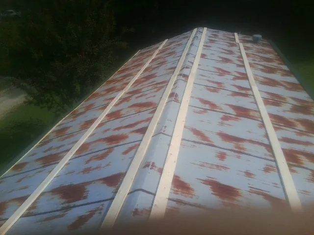 Rusted metal roof panels with new wood purlins before replacement — Storm Damage Roof Repair in Reynolds by Roofing Brothers