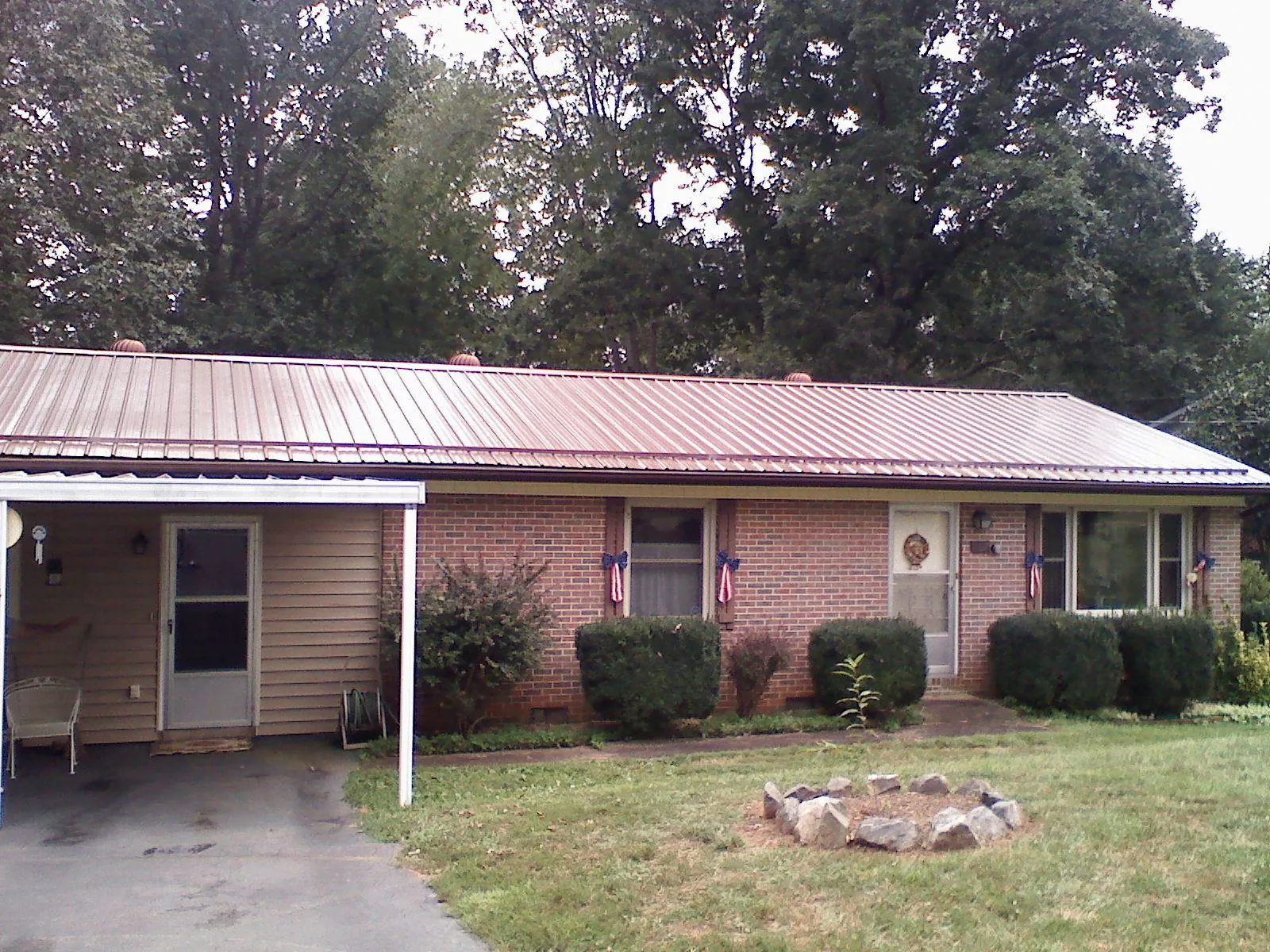 Bronze metal roof and carport on a brick ranch home — Roof Repair work by our crew in Reynolds