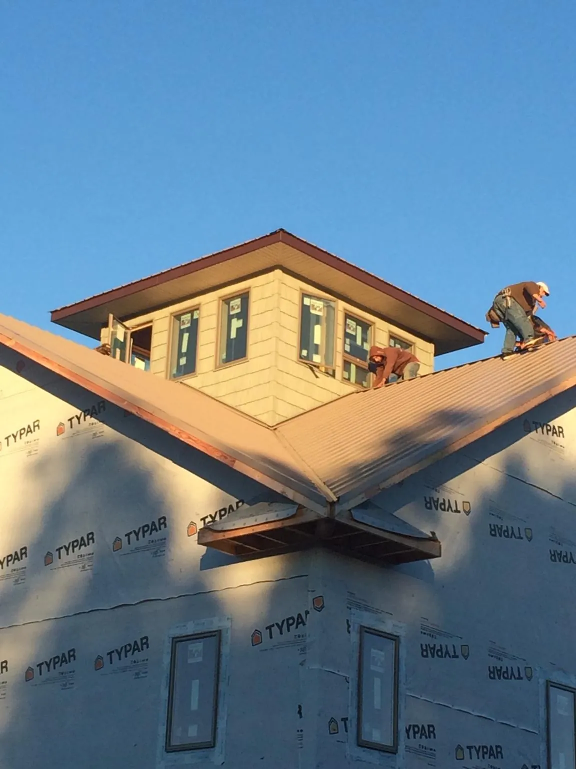 Roofers working around a rooftop cupola on a new metal roof at sunset — Roof Waterproofing in Reynolds by Roofing Brothers